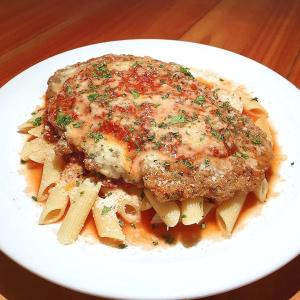 a plate of pasta with a piece of meat at Jacarandá Palace Hotel in Teixeira de Freitas