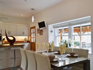 a kitchen with a dining room table with white chairs at Ladybird Cottage in Lochend