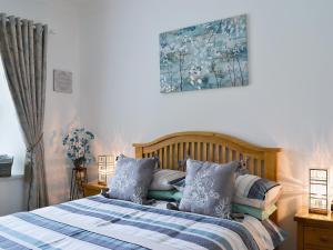 a bedroom with a bed and a painting on the wall at Ladybird Cottage in Lochend