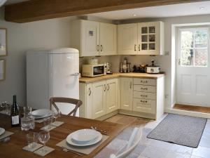 a kitchen with a table and a white refrigerator at Maison De Quai in Cley next the Sea