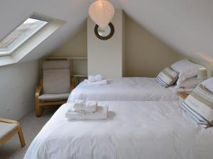 a attic bedroom with two beds and a window at Maison De Quai in Cley next the Sea