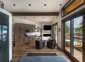 une cuisine avec des placards en bois et des chaises noires dans une maison dans l'établissement Wild Renfrew Seaside Cottages, à Port Renfrew