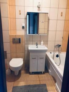 een badkamer met een wastafel, een toilet en een bad bij Apartament Kilińskiego w centrum Ustki in Ustka