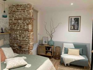 - un salon avec un lit et un mur en briques dans l'établissement LE SAINT CYP - Toulouse - appart entier cosy et au calme, proche du métro, à Toulouse
