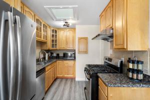 La cuisine est équipée d'armoires en bois et d'un réfrigérateur en acier inoxydable. dans l'établissement Cozy 2 Bedroom Home Near SFO with Private Parking, à San Bruno