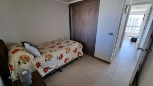 a bedroom with a bed with a floral bedspread at Departamento Marina Horizonte II in Coquimbo +36 photos