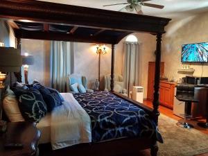1 dormitorio con cama con dosel y TV en Tuscan Manor, en Eureka Springs