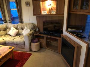 a living room with a couch and a flat screen tv at First Steps Caravan Rentals in Sandown