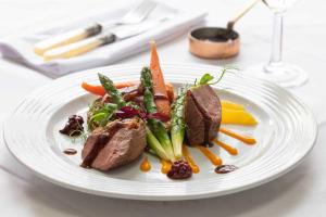 a plate of food with meat and vegetables on a table at Worcester Bank House Hotel Spa & Golf; BW Premier Collection in Worcester