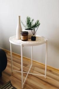 a white table with plants and a vase on it at LK Apartment in Rēzekne