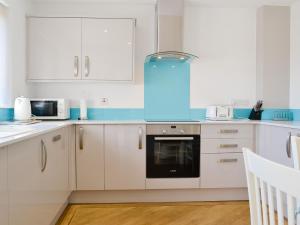 a kitchen with white cabinets and a blue appliance at Harbour Gates in Maryport