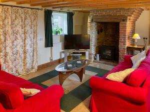 a living room with two red chairs and a fireplace at Hawthorne Cottage in Preston