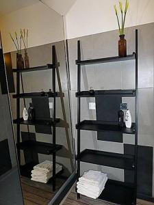 La salle de bains est pourvue d'étagères noires, de serviettes et d'un miroir. dans l'établissement F3 80m², vue sur mer. Arrivée possible en semaine, à Calcatoggio