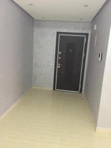 um corredor com uma porta preta e um piso branco em Appartement à casablanca em Tafza