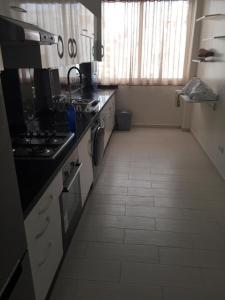 Appartement à casablanca في Tafza: مطبخ مع أرضية بيضاء من البلاط مع موقد