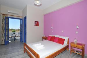 a bedroom with a bed with a purple wall at Nikolas Villas in Perivolos