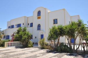 un bâtiment blanc avec des palmiers devant lui dans l'établissement Nikolas Villas, à Perivolos