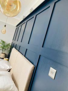 a bedroom with a blue wall with a bed and a switch at The Morley in Torquay