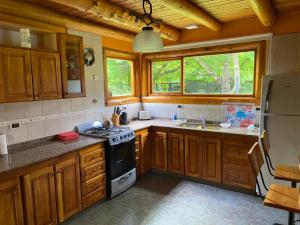 Una cocina con gabinetes de madera y un horno de estufa. en Lo de Andre, en Lago Puelo 12 fotos más