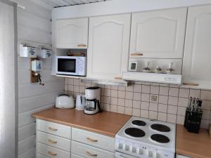 a kitchen with white cabinets and a stove and microwave at Villa Bear's in Rovaniemi