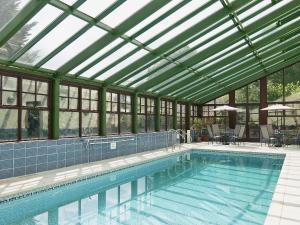 uma piscina com tecto de vidro e uma piscina em St Andrews Barn em Necton