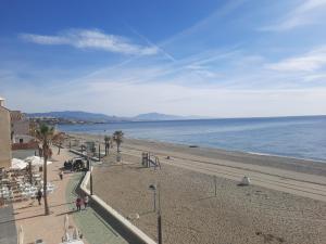 een uitzicht op een strand met palmbomen en de oceaan bij Primera linea de Playa a 10 min Estepona in San Luis de Sabinillas