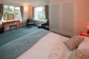 a bedroom with a large bed and a desk and chairs at Mountain Cross in Gatehouse of Fleet