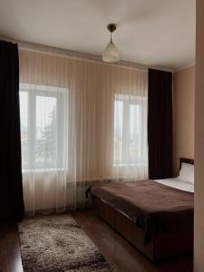 ein Schlafzimmer mit einem Bett und zwei Fenstern in der Unterkunft Козацькі Забави in Riwne