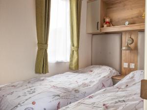 a small bedroom with a bed and a window at The Willows in Stonham Aspall
