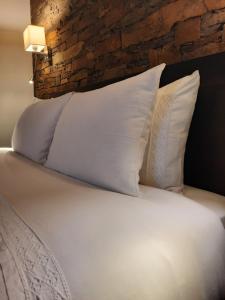 a bed with white pillows and a brick wall at Casa da Eira de Cima in Chão Sobral