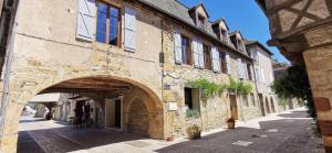 - un bâtiment en pierre avec une arche dans une rue dans l'établissement Maison Pierre Loti, gîte historique et spacieux en vallée de la Dordogne, à Bretenoux