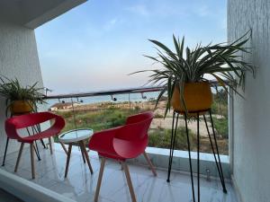 a balcony with three chairs and a window with plants at HMS SEA VIEW VILLA in Accra