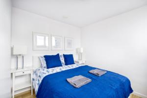 Biała sypialnia z niebieskim łóżkiem i biurkiem w obiekcie Central Family Apartment w Warszawie