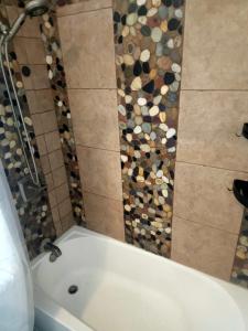 a white bath tub in a bathroom with a mosaic wall at Hidden Gem Guest House in Panama City Beach +15 photos