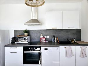a kitchen with white cabinets and a black oven at Lakeside Provence - Appartement 4 étoiles face au lac de Monteux in Monteux