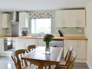 a kitchen with a wooden table with a vase of flowers on it at Roaches View Barn in Wetleyrocks