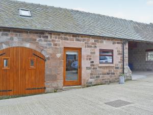 a brick building with a wooden door and a garage at Roaches View Barn in Wetleyrocks