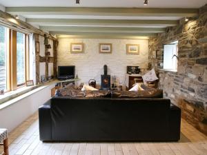 a living room with a black couch in a room with a stone wall at Meadow Barn in Shelve