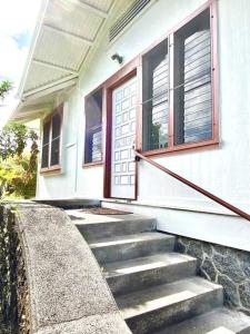 une maison blanche avec des escaliers menant à une porte dans l'établissement YOUR HILO HOMEBASE - Lovely 3 Bedroom in Heart of Hilo with AC!, à Hilo
