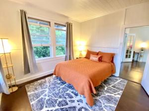 a bedroom with a bed with an orange blanket and a window at YOUR HILO HOMEBASE - Lovely 3 Bedroom in Heart of Hilo with AC! in Hilo