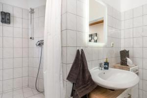 La salle de bains blanche est pourvue d'un lavabo et d'une douche. dans l'établissement Gemütliche Wohnung mit Billiard-/Airhockeytisch und Netflix, à Cassel