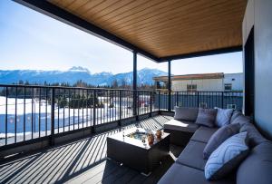 a living room with a couch on a balcony with mountains at The Big Deck by Revelstoke Vacations in Revelstoke