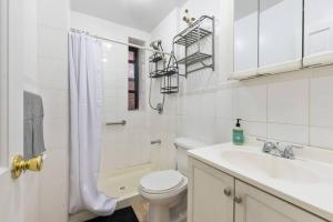 Lovely 3 bedroom apartment in NYC 2 في نيويورك: حمام ابيض مع مرحاض ومغسلة