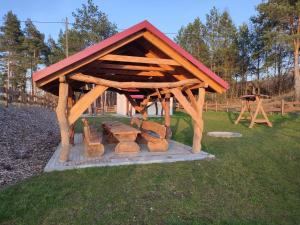 a wooden pavilion with a picnic table in the grass at Domek pod sosnami in Gaj