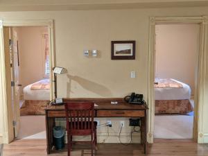 a desk in a room with a bedroom with two beds at Third Mission Heritage Suites in Peace River