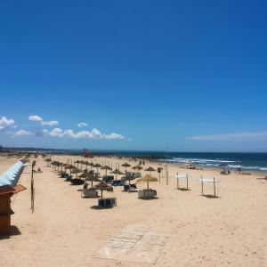 een strand met veel stoelen en parasols erop bij Sal Guest House in Costa da Caparica