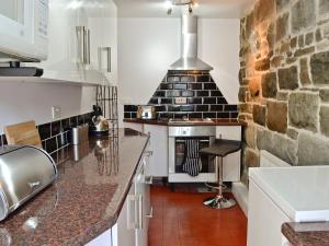 a kitchen with a stove and a stone wall at Ty Capel Gosen in Trevor