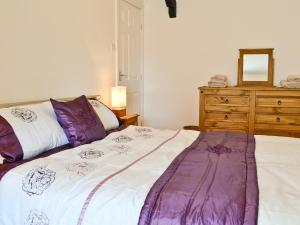 een slaapkamer met een groot bed met paarse kussens en een dressoir bij Ty Capel Gosen in Trevor