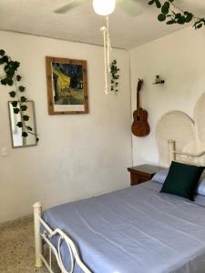 a bedroom with a bed and a guitar on the wall at Sobre Costera, 1min La Quebrada, 3m playas/yates in Acapulco