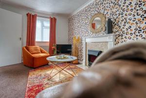 a living room with a fireplace and a chair and a mirror at CAPRI 13 SA - Cosy 2 bed house, Close to M1 & Loughborough University, Free WIFI, Free PARKING, - Ask for contractor rates! in Loughborough